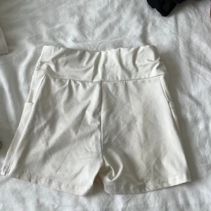 Vita höga shorts från Shein XS - Snygga vita shorts från Shein i storlek XS med hög midja och praktiska fickor på sidorna. Tillverkade i mjuk bomullsmix som känns skön mot huden. Perfekta för varma sommardagar och har en clean, enkel look som är lätt att matcha.