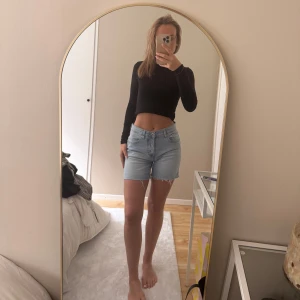 Ljusblå jeansshorts - Säljer ett par ljusblå jeansshorts med normal passform och hög midja. Klassisk femficksmodell med bälteshällor och dragkedja. Perfekta för sommaren och lätta att matcha med olika toppar.