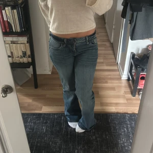 Blå bootcut jeans - Säljer ett par klassiska blå bootcut jeans med normal passform och låg midja. Jeansen har fem fickor, dragkedja och knapp framtill. Perfekta till vardags för en avslappnad men snygg look. 💌Köparen står för frakten!