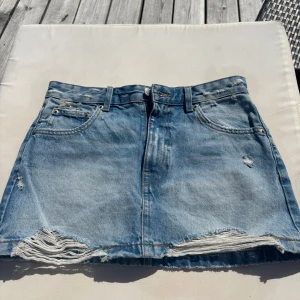 Ljusblå jeanskjol från Pull&Bear - Säljer en ljusblå jeanskjol från Pull&Bear med slitna detaljer. Endast använd fåtal gånger.