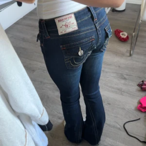 True Religion mörkblå bootcut jeans - Säljer ett par mörkblå jeans från True Religion med bootcut passform. Byxorna är i modellen joey och storlek 24. Byxorna är lite nedtrampade då dom är lite långa för mig och har ett litet hål längst ner, inget märkbart när man har dom på sig dock. 
