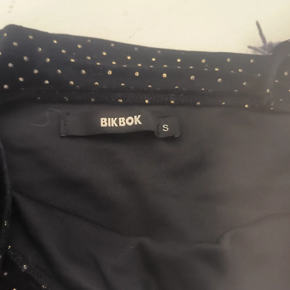 Säljer en svart linnetopp från Bik Bok med små guldprickar. Toppen har smala axelband och är perfekt för en stilren look. Passar bra till både jeans och kjol. Storlek S men passar även M. . Yläosat.
