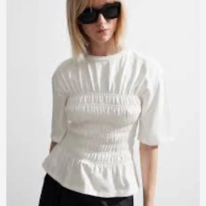 Vit blus med smockdetaljer från & other stories - Säljer en stilren vit blus med smockdetaljer som ger en fin passform. Blusen har trekvartsärmar och en lätt volang vid nederkanten. 