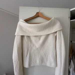 Vit ribbad offshoulder tröja från H&M - Säljer en stilren vit ribbad tröja med offshoulder-design. Tröjan har långa ärmar och en bred krage som ger en elegant look. 