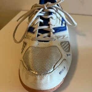 Vita och blå sneakers från Pro Touch - Snygga vita och blå sneakers från Pro Touch med snörning och en sportig design. Skorna har en vit bas med blå detaljer och en gummisula som ger bra grepp. Perfekta för träning eller en aktiv vardag.