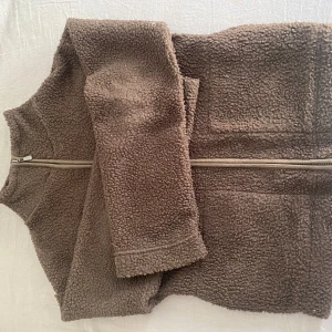 Brun teddyjacka med dragkedja - Mysig brun teddyjacka med dragkedja framtill. Den har två praktiska fickor framtill.