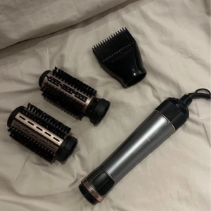 Hårstyler med tillbehör - Säljer en Remington hårstyler med flera tillbehör. Inkluderar två borsthuvuden och en kam för olika stylingalternativ. Perfekt för att skapa volym och släta ut håret. Stilren design i silver och svart. Test Använt  1 gång men fungerade inte på mig! Nu är den bara i mitt rum och kan komma till användning för någon annan än att bara ligga och damma❤️köpt för 799kr 