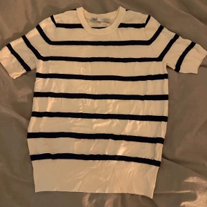 Vit och marinblå randig tröja från Zara - Säljer en vit och marinblå randig tröja från Zara. Tröjan har korta ärmar och en normal passform, perfekt för en avslappnad stil. Den är gjord i ett mjukt material som känns skönt mot huden.