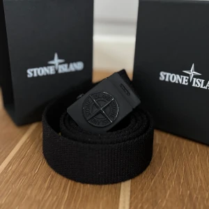 Svart bälte från Stone Island - Snyggt svart bälte från Stone Island med en stilren design. 