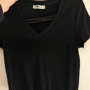 Svart v-ringad t-shirt från Fruit of the Loom - Säljer en klassisk svart t-shirt från Fruit of the Loom. Den har en stilren v-ringning och korta ärmar, perfekt för en enkel och snygg look. Passar till det mesta och är ett måste i garderoben!