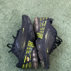 Nike Air Max Plus i svart och gul/grön - Säljer ett par Nike Air Max Plus i svart med gula detaljer. Skorna har en unik design med synlig Air Max-dämpning och snörning. Perfekta för dig som vill ha en sportig och stilren look.(storlek 38,5 men funkar perfekt till någon mindre eller större storlek)