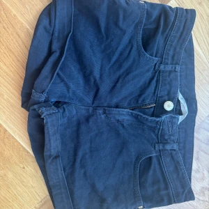 Svarta shorts  - Säljer ett par svarta shorts med hög midja och praktiska fickor både fram och bak. De har en dragkedja och knapp framtill för enkel stängning. Perfekta för en avslappnad stil.
