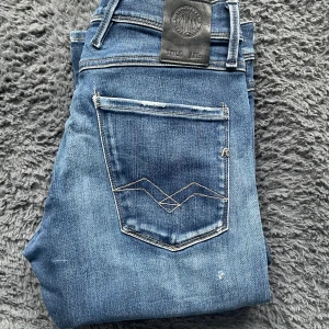 Replay anbass hyperflex jeans  - Snygga blå jeans från Replay i modellen Anbass Hyperflex. De har en klassisk femficksdesign och en modern slim passform. Perfekta för en stilren look. Storlek 29/32