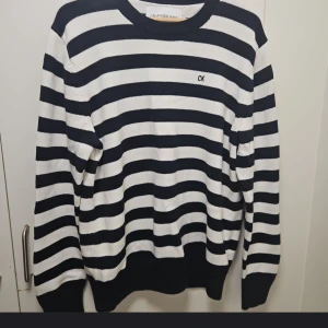 Randig tröja från Calvin Klein Jeans - Säljer en stilren randig tröja från Calvin Klein Jeans i svart och vit. Tröjan har långa ärmar och en klassisk rund halsringning. Perfekt för en avslappnad och trendig look.