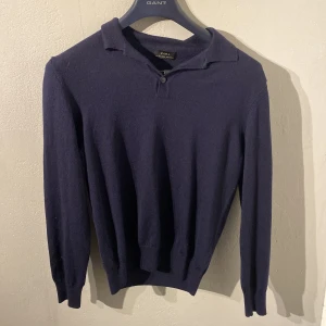 Mörkblå tröja från Zara - Säljer en stilren mörkblå tröja från Zara med krage och knappdetalj framtill. Tröjan har långa ärmar och är tillverkad i ett mjukt material som passar perfekt för kyligare dagar.