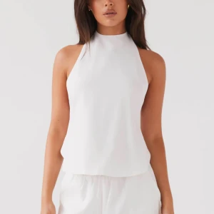 Vit haltermecktopp med knytband - Säljer en stilren vit halternecktopp i linne.  Toppen har knytband i ryggen och är perfekt för varma sommardagar eller en kväll ute. Köp från peppermayo för 650kr. Lappen kvar 