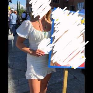 Studentklänning - Säljer en söt vit kortklänning med puffiga kortärmar och rynkade detaljer framtill. Perfekt för sommaren/studenten. Storlek M men stretchig i materialet så passar även S/L