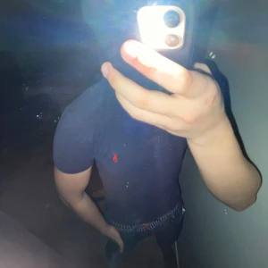 Blå pikétröja från Ralph Lauren - Säljer en klassisk blå pikétröja från Ralph Lauren med den ikoniska röda loggan på bröstet. Tröjan har en krage med två knappar och korta ärmar. Perfekt för en stilren och avslappnad look. Bra skick.