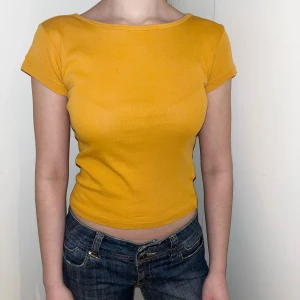 Gul topp från Gina Tricot - Säljer en snygg gul croppad topp från Gina Tricot. Toppen har korta ärmar och en tight passform, perfekt för en trendig look. Den är gjord i ett mjukt material som känns skönt mot huden.