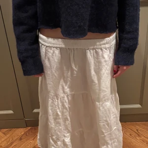 Vit långkjol - Säljer en vit långkjol i ett luftigt och bekvämt material. Kjolen har en elastisk midja för en skön passform. Perfekt för varma dagar eller som en del av en lager-på-lager-look.