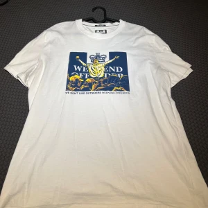 Vit t-shirt från Weekend Offender - Säljer en vit t-shirt från Weekend Offender med ett stort tryck på framsidan. Trycket visar en person med utsträckta armar och texten 'WE DON'T LIKE OUTSIDERS'. Perfekt för en avslappnad stil.