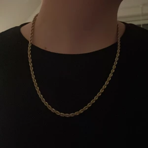 Guldfärgat halsband med tvinnad design - Snyggt guldfärgat halsband med en elegant tvinnad design. Perfekt för att ge en stilren touch till din outfit. Halsbandet har en klassisk låsning som gör det enkelt att ta på och av.