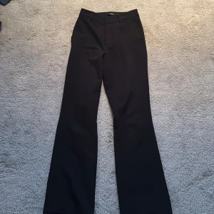 Svarta kostymbyxor från BikBok - Snygga svarta kostymbyxor från BikBok i storlek 34. Byxorna har en klassisk design med raka ben och en stilren look. Perfekta för en chic och elegant stil.