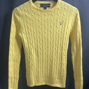 Gul kabelstickad tröja från GANT - Säljer en snygg gul kabelstickad tröja från GANT. Tröjan har en klassisk rund halsringning och långa ärmar. Perfekt för att liva upp garderoben med lite färg! 💛ny pris 1200
