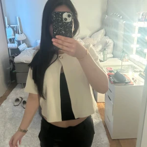 Beige bolerotopp - Säljer en stilren beige bolerotopp med korta ärmar. Perfekt för att lägga till en touch av elegans till din outfit. Toppen är croppad och har en enkel design som gör den lätt att matcha med olika plagg. Pris kan diskuteras💞