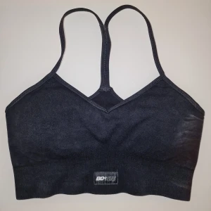 Svart sportbh från Bo+Tee - Toppen har en v-ringad design med smala axelband och ribbad nederkant som formar bra runtom. Perfekt för träning.