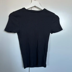 Svart t-shirt från bikbok - En fin ribbad, tajt, svart t-shirt från Bikbok. Skriv om intresserad❤️
