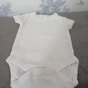 Vit kortärmad body från Newbie - Säljer en söt vit kortärmad body från Newbie i storlek 50. Perfekt för de allra minsta. Bodyn har praktiska knappar i grenen för enkel på- och avklädning. Ett måste i basgarderoben för små barn! 🍼