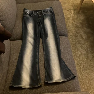 Blå jeans med utsvängda ben - Snygga blå jeans med en cool tvätt och utsvängda ben. De har en knapp med unik design och klassisk dragkedja. Använd ett par gånger! En liten fläck vid byxslutet men inget man tänker på! Kom privat för mer bilder! Midjan är 27 och längden är 30, priset kan diskuteras❤️Den sista bilden är hur byxorna ser ut på mig❤️