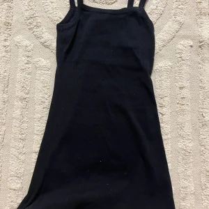 Svart ribbad klänning från Djerf Avenue - Snygg svart ribbad klänning från Delaravenue med smala axelband. Perfekt för en stilren look. Klänningen är kort och har en tight passform som framhäver figuren.