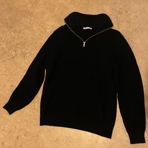 Mörk Blå stickad tröja från Zara - Säljer en stilren svart stickad tröja från Zara med dragkedja vid halsen. Perfekt för kyligare dagar med sin höga krage och långa ärmar. Tröjan är både bekväm och snygg, ett måste i garderoben! Är lite använd men gott som ny!
