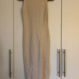 Beige ärmlös klänning från Moocci - en lång stretchig klänning från mocci. använd ett fåtal gånger, säljer eftersom den inte kommer till användning. storlek står inte men den passar utmärkt på mig och jag är ungefär en S i klänningar. det är finstickat tyg så lite varmare är den!