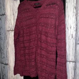 Vinröd stickad kofta från Exlindexlind - Säljer en vinröd stickad kofta från Exlindexlind. Koftan har ett vackert hålmönster och knäppning framtill. Perfekt för att hålla sig varm och stilren under kyligare dagar. Passar bra till både jeans och kjol. 🍂