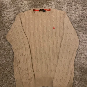 Beige stickad tröja från Morris - Säljer en stilren beige stickad tröja från Morris med ett diskret rött broderi på bröstet. Tröjan är storlek S. Skick 8/10                                                                          Tveka inte att fråga frågor 💯