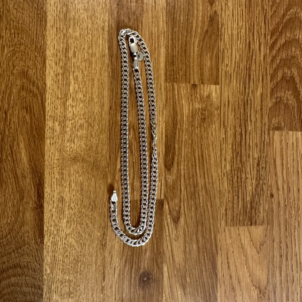 Snyggt silverfärgat halsband med en klassisk kedjedesign. Perfekt för att ge en stilren touch till din outfit. Halsbandet är även äkta och de står även 925 som betyder att silver kedjan är äkta. Asusteet.