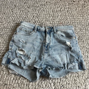 Ljusa slitna jeansshorts från H&M - Snygga ljusblå jeansshorts från H&M med slitningar framtill. Perfekta för varma dagar och festivalhäng. Använda fåtal gånger men i bra skick. Storlek 38 men passar mig som har 34/36. Medelhöga men går att vika ner till lågmidja.