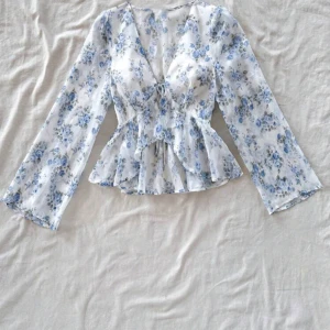 Blommig blus med knyt - Supersöt blus i vitt med blått blommönster, v-ringning och knyt framtill. Tunt, genomskinligt material men extra tyg vid brösten som ni ser på bilden. Aldrig använd alldeles för liten vid brösten för mig (jag har 75B). Den är S men vid brösten känns som XS, min syster använt en gång så lappar inuti är bort klippta. Men kom ihåg att den är liten vid bröst området så passar nog A (Jag har B och går inte att knyta alls bra), så du blir nöjd bara💕
