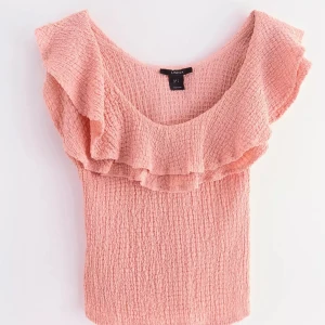 Rosa volangtopp från Lindex - Supersöt rosa topp från Lindex med volangdetalj över axlarna och smockad struktur. Toppen är ärmlös och har en mjuk, luftig känsla som passar perfekt till varma dagar. Den har en feminin och trendig look med bred urringning. Pris kan diskuteras vid snabb affär💓