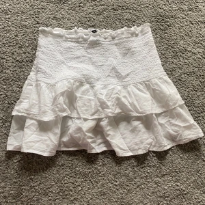 Vit volangkjol från H&M Divided XS - Supersöt vit kortkjol från H&M Divided i storlek XS. Kjolen har smockad midja och dubbla volanger💗