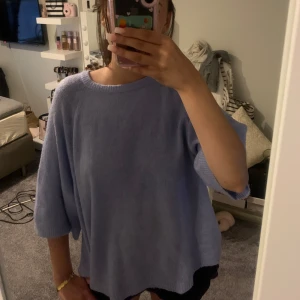 Ljuslblå stickad t-shirt - Supermjuk och oversized stickad tröja i ljusblå Tröjan har rund halsringning och trekvartsärmar, perfekt för lager på lager. Enkel och stilren design som är lätt att matcha med jeans eller kjol.