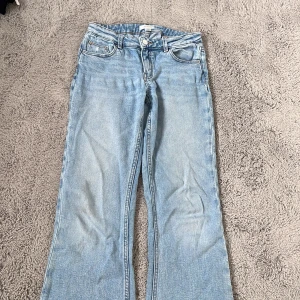 Ljusblå bootcut jeans Gina Tricot - Snygga ljusblå jeans från Gina Tricot i klassisk bootcut-modell. Jeansen har fem fickor, normalhög midja och är tillverkade i mjukt bomullsjeans. Perfekta för dig som gillar en avslappnad och trendig look.
