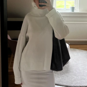 Vit polotröja i oversized modell - Säljer en vit polotröja med oversized passform och ribbade detaljer vid krage, ärmslut och nederkant. Tröjan har lång ärm och hög, bred polokrage. Superskönt material, men tyvärr lite nopprig i ärmar och längst ner på kanten. Övrigt bra skick. 