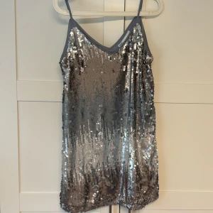  Paljettklänning  - Säljer en glittrig silverfärgad klänning med tunna axelband och v-ringning. As snygg till fest❣️