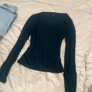 Mörkblå långärmad topp från bikbok - En enkel och stilren mörkgrönlångärmad topp från bikbok. Modellen är tight med rundad halsringning och mjukt, stretchigt material som sitter snyggt på kroppen. Perfekt att matcha med jeans eller kjol för en clean look.