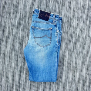 Blå jeans från Jacob Cohen - Snygga blå jeans från Jacob Cohen med klassisk femficksdesign och ljus tvätt. Jeansen har kontrastsömmar och en läderpatch med logga bak i midjan. Perfekta för en avslappnad och trendig look.!AI BESKRVINING! Om ni vill ha fler bilder eller om ni har andra funderingar och frågor skriv.