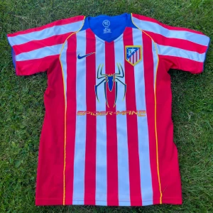 Atletico Madrid - Säljer en unik Atletico Madrid fotbollströja från Nike i storlek M. Tröjan har röda och vita vertikala ränder, blå detaljer och gult kantband. På bröstet finns Spider-Man 2-tryck och klubbmärke, Torres och nummer 9 på ryggen. 